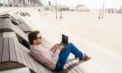 Man working on a laptop on the beach.