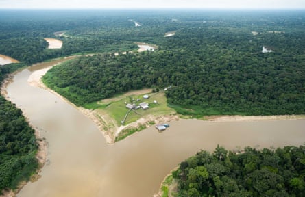 Aerial view of the confluence of two rivers with a group of buildings in the middle, surrounded by forest