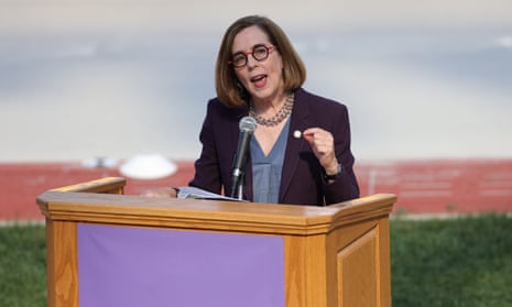Kate Brown stands at a lectern in front of a microphone speaking.