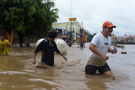 People wade through a flooded street after torrential rains that caused an overflow of rivers in Poza Rica