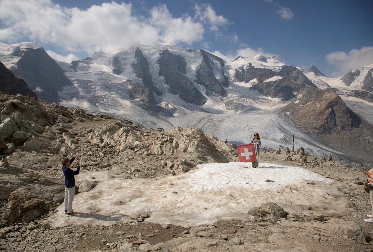 Seorang wanita berpose di sebelah bendera nasional Swiss di dekat Gunung Piz Palue