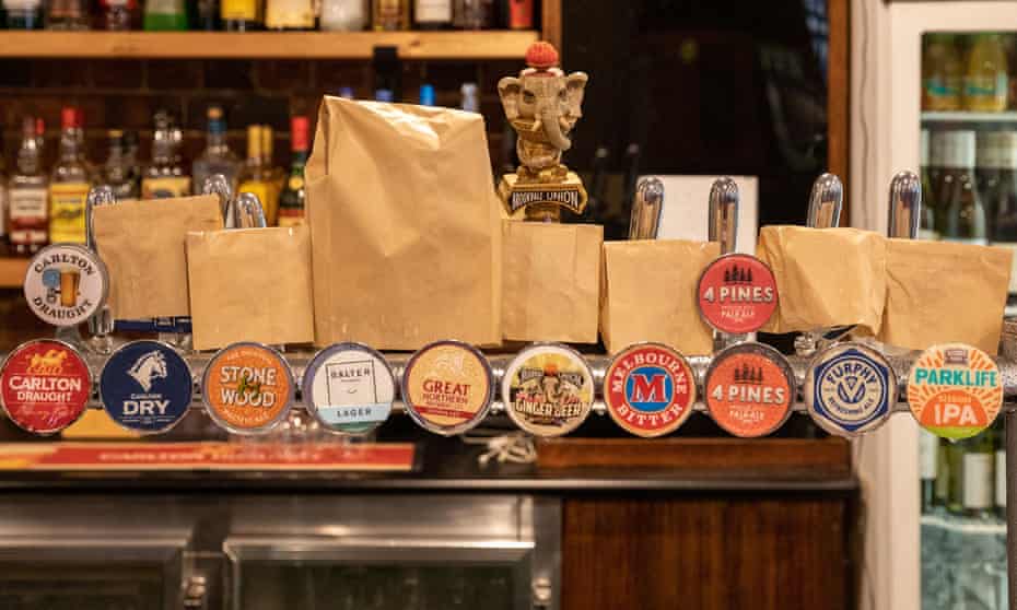 Paper bags are seen placed on top of beer taps indicating that certain brands of beer are unavailable due to Covid
