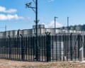 A high security fence with razor wire and surveillance cameras surrounds a data centre facility.