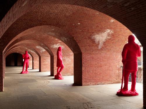 three red figures beneath brick arches