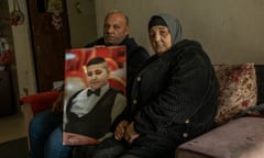 Ali and Rawiya sit on a sofa holding a photo of Rami