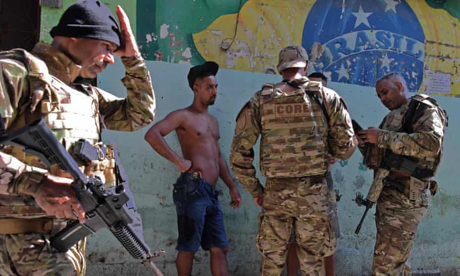Members of the special operations wing of the Brazilian Civil Police check the identity of two men during an occupation of Jacarezinho favela in Rio de Janeiro