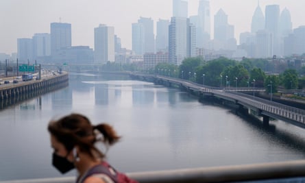 A person wearing a protective face mask walks past the skyline in Philadelphia.