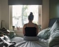 Rear view of a teenage girl looking out of the window whilst sitting on her bed