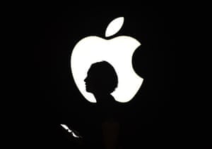 Silhouette of someone in front of a lit Apple logo
