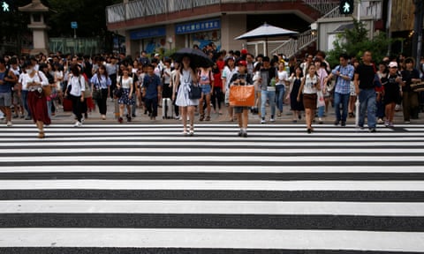 People walk on a crosswalk at a shopping district in Tokyo, Japan.