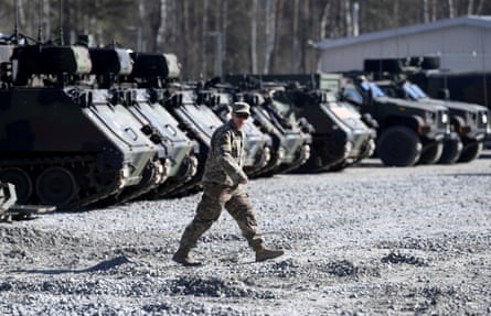 A military service member walks in front of a line of tanks