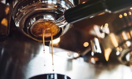 Fresh and hot espresso coffee pours from a portafilter on a nice chrome espresso machine