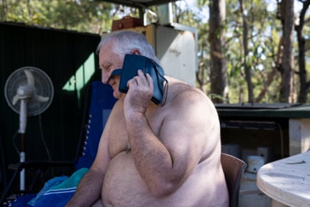 Naked middle-aged man sitting on a chair talking on a mobile phone