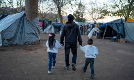 A man and his children through a campsite of Mexican asylum seekers in Ciudad Juarez. Mexican literary figures say their criticism of American Dirt has been silenced.