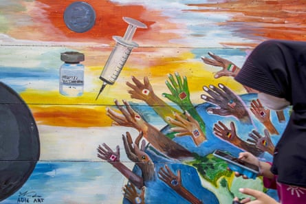 A woman passes a Covid vaccine mural in Tangerang, Banten, Indonesia.