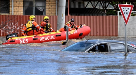 Emergency workers look at a submerged car on a flooded street in the Melbourne suburb of Maribyrnong