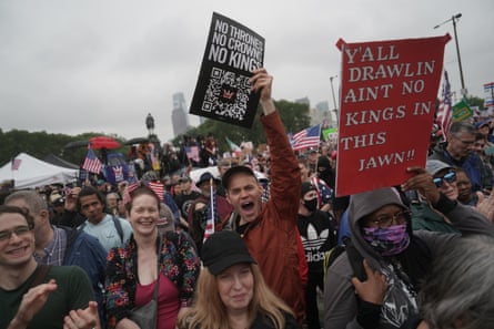 people hold signs that read ‘no thrones no crowns no kings’ and ‘y’all drawlin ain’t no kings in this jawn’