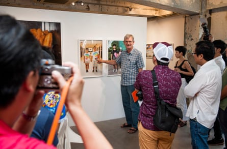 Martin Parr gestures to picture on wall while people look on
