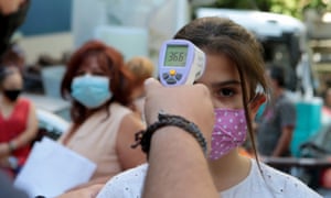 A student gets her temperature checked before attending school in Athens on Monday.
