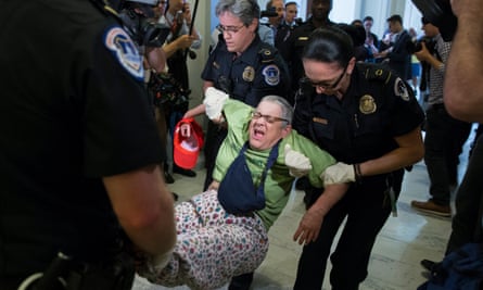Capitol police carry out a demonstrator protesting outside Mitch McConnell’s office.