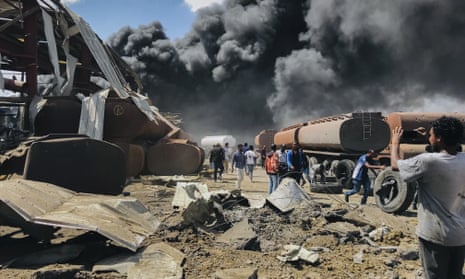 People in front of clouds of black smoke from fires in the aftermath at the scene of an airstrike in Mekele, the capital of the Tigray region.