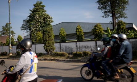People on mopeds drive past the VKG garment factory in Mae Sot, Thailand