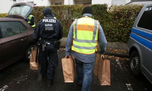 Police officers carry away items confiscated during an apartment raid in Bonn.