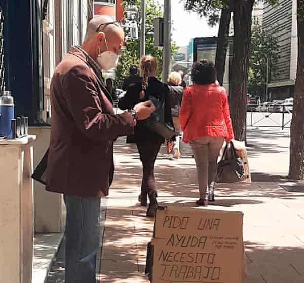 Un hombre con una tabla de cartón, buscando trabajo.