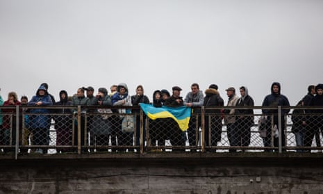 Residents wave flags and wait to receive the first train to arrive in Kherson since the start of the Russian invasion.