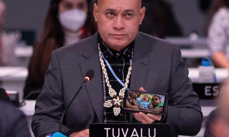 A Tuvalu delegate, holding up a photograph of three children on his mobile, speaks during a plenary session at Cop26.