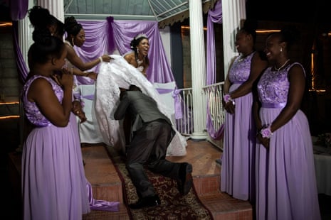 Stanley Joseph tries to remove the bride’s garter from underneath her dress, as their bridesmaids look on, during a wedding game in Port-au-Prince