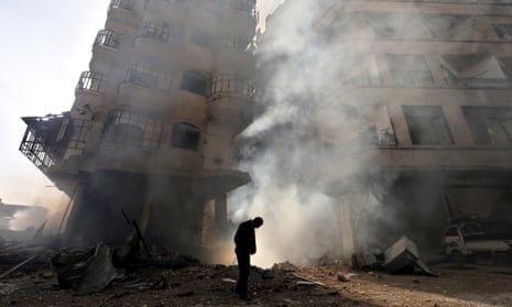 A man walking in front of a burning building after a Syrian Air force air strike in Damascus in January 2013