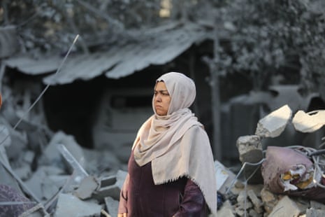 A woman stands in front of destroyed buildings after Israeli airstrikes in Khan Younis, a city located in the south of Gaza Strip where the Israeli military has ordered residents to evacuate to for safety.