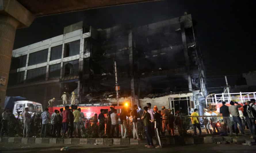 People look on from the street at the charred remains of the Delhi office building.