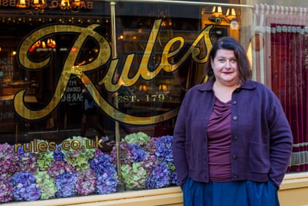 A woman stands in front of a restaurant which reads ‘Rules’