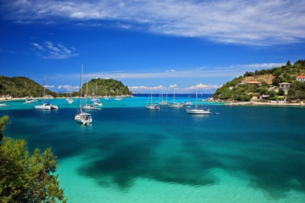 calm blu-green bay with sailing boat anchored and protected by forested hills