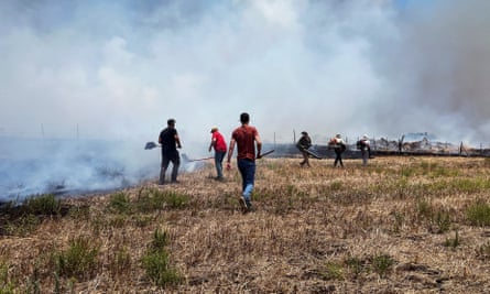 People work to put out fires in dry field