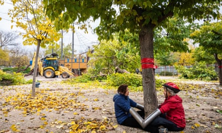 Two campaigners linked by metal tubes sitting together at the bottom of a tree