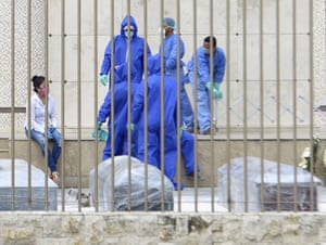 Relatives and the staff of Jardines de la Esperanza cemetery wait to bury victims in coffins which authorities have wrapped with plastic