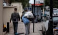 Two men walking down London street, one carrying a see-through plastic bag of belongings.