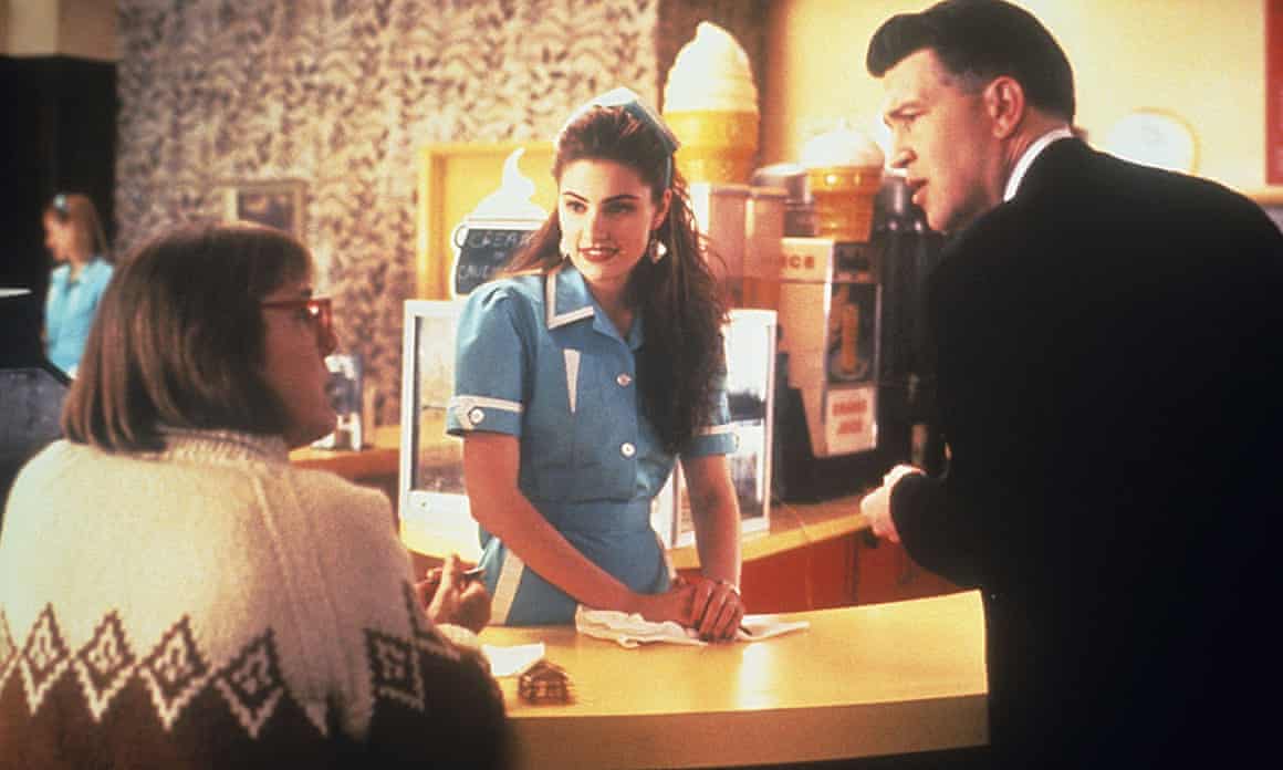 Three people around table, two of them standing