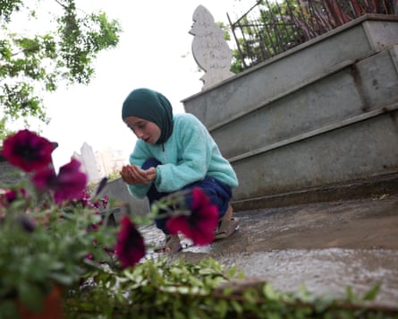 A displaced girl from Tyre prays in front of a grave at a Shia cemetery in Sidon, Lebanon