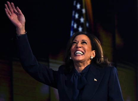 A smiling Kamala Harris raises her hand.