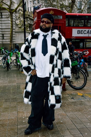 A person wearing a black-and-white checked furry coat and black trousers