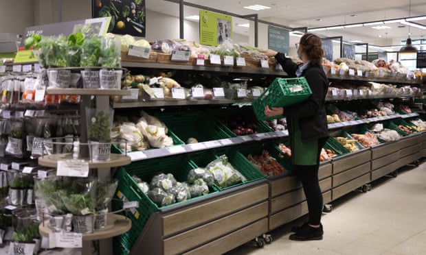A ‘partner’ stacking shelves at a Waitrose supermarket.
