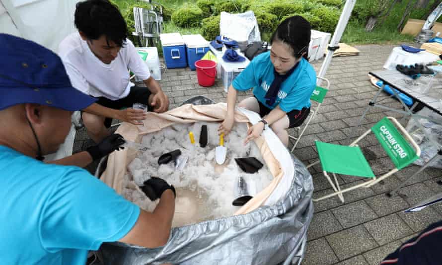 Dobrovoľníci pripravujú pre divákov balíčky ľadu počas testovacej akcie plážového volejbalu na Tokio 2020