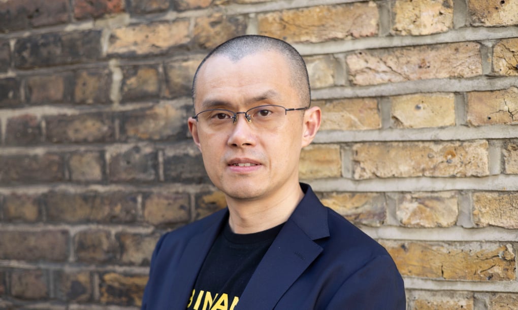 Close-up of Changpeng Zhao looking asteadily into the camera with the backdrop of an old brick wall