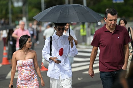 A man uses an umbrella to protect himself from the sun as he enters the Cop30 summit.