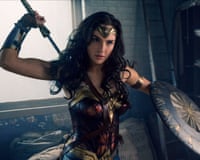 Wonder Woman raises a sword, wearing armor and holding a shield, in a film scene