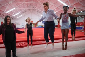 Nicola Sturgeon and Katy Loudon hold hands with two young girls as they all bounce on a trampoline